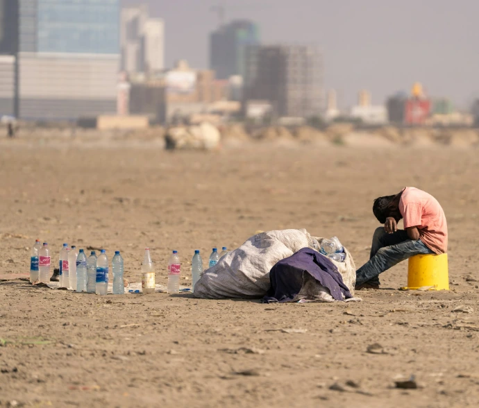 Man sitting on bucket with bottles and trash